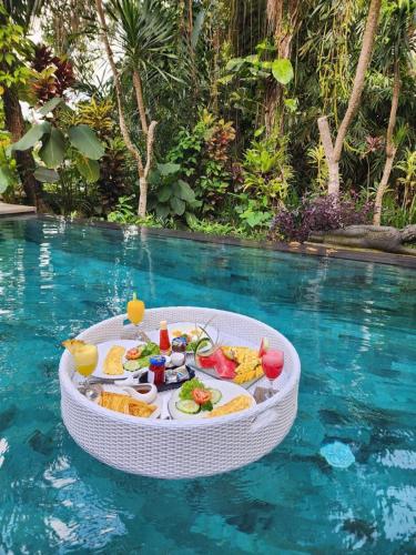 a tray of food in the water next to a swimming pool at Luxury 3BR Infinity Jungle View Aashaya Villa Ubud in Ubud