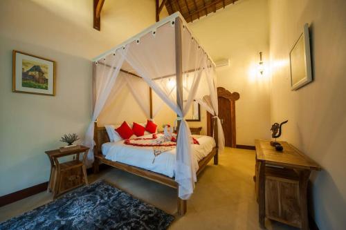 a bedroom with a canopy bed with red pillows at Luxury 3BR Infinity Jungle View Aashaya Villa Ubud in Ubud