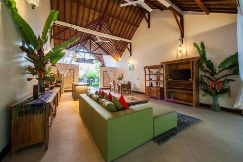 a living room with a green couch and a television at Luxury 3BR Infinity Jungle View Aashaya Villa Ubud in Ubud
