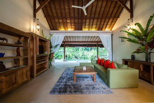 a living room with a green couch and a table at Luxury 3BR Infinity Jungle View Aashaya Villa Ubud in Ubud