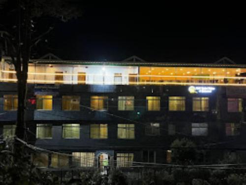 een gebouw 's nachts met een trein voorbij bij Hotel Kasturi Palace & Restaurant Darjeeling in Darjeeling