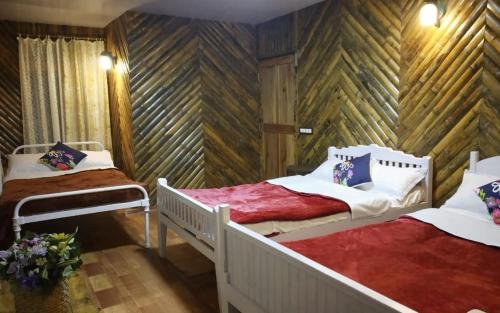 two beds in a room with wooden walls at Koilee Homestead by StayApart in Darjeeling