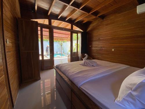 een groot bed in een kamer met houten wanden bij Rascal House Gili Trawangan in Gili Trawangan