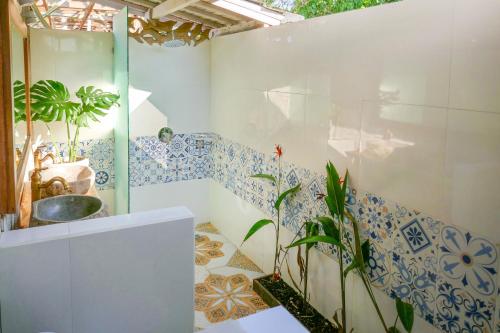 uma casa de banho com azulejos azuis e brancos na parede em Lembo Lagoon Bungalows em Nusa Lembongan