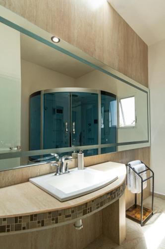 a bathroom with a sink and a large mirror at Lujosa casa: alberca terapéutica 3x2m, chimenea, cocina profesional in León