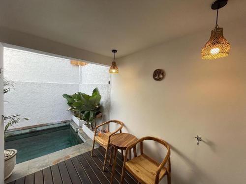 un patio con 2 sillas y una piscina en LaKalena Private Villa Bali, en Ketewel