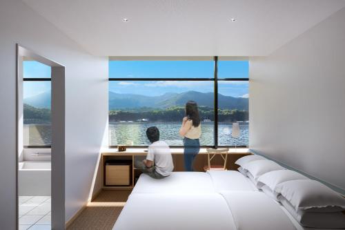 a man and a woman standing in a room with a large window at BONAPOOL in Onomichi