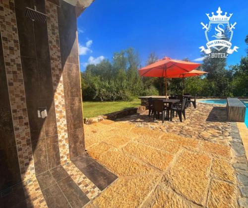 a patio with a table and an umbrella next to a pool at La Villa de San Sebastian Hotel in Villa de Leyva