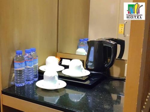 a hotel room counter with bottles of water and cups at Magallanes Square Hotel Inc. in Tagaytay