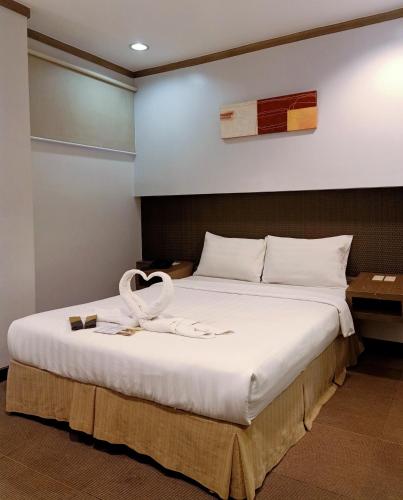 a bedroom with a large bed with a ribbon on it at Magallanes Square Hotel Inc. in Tagaytay