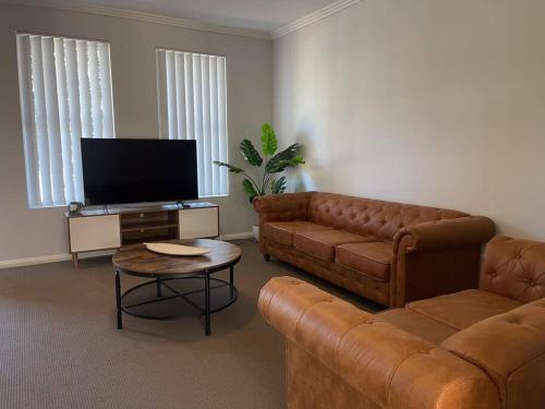 Una sala de estar con un sofá y un televisor. en Serene Wagga Townhouse Getaway, en Wagga Wagga