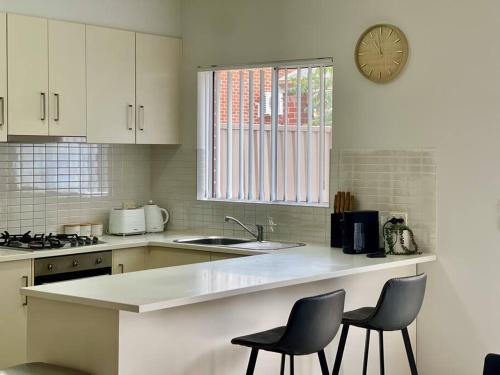 una cocina con 2 sillas y un reloj en la pared en Serene Wagga Townhouse Getaway, en Wagga Wagga