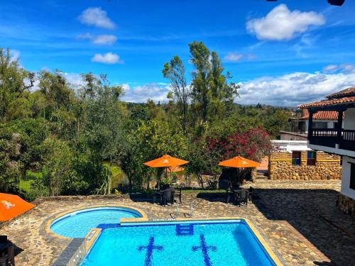 a swimming pool with two umbrellas and two pools at La Villa de San Sebastian Hotel in Villa de Leyva