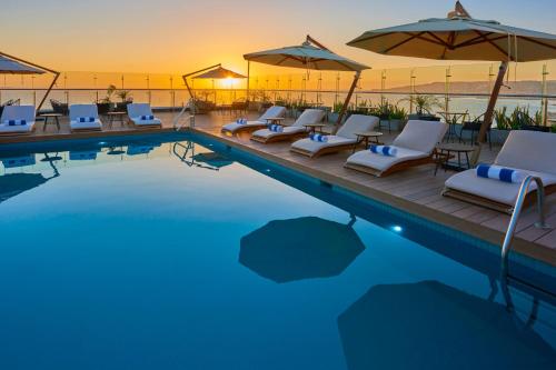 a swimming pool with lounge chairs and umbrellas at City Express Plus by Marriott Ensenada in Ensenada