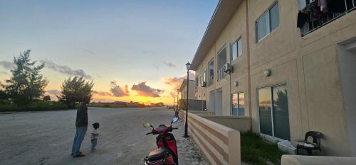 un enfant debout à côté d'une moto à côté d'un bâtiment dans l'établissement Sunset View, à Kulhudhuffushi