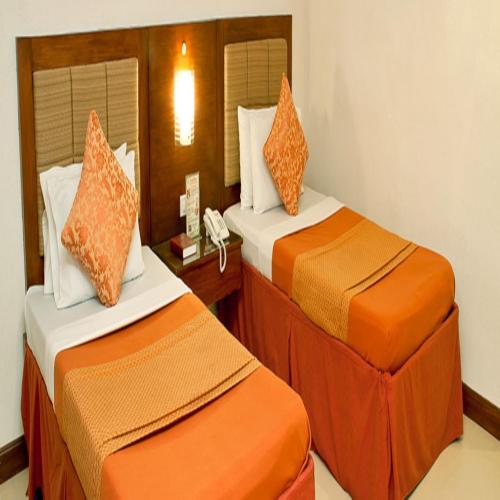 Dos camas en una habitación de hotel con naranja y blanco en Royal Garden Hotel, en Ozamis