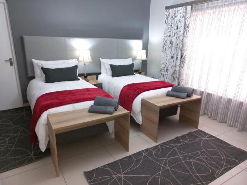 a hotel room with two beds and two tables at Cronin Luxury Accomodation Room 3 in Kimberley