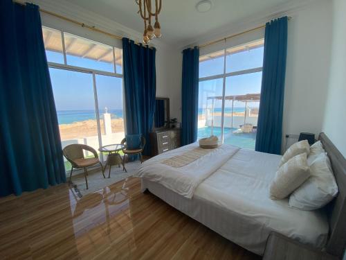 a bedroom with a bed and a view of the ocean at Wadi shab guest house in Ţīwī