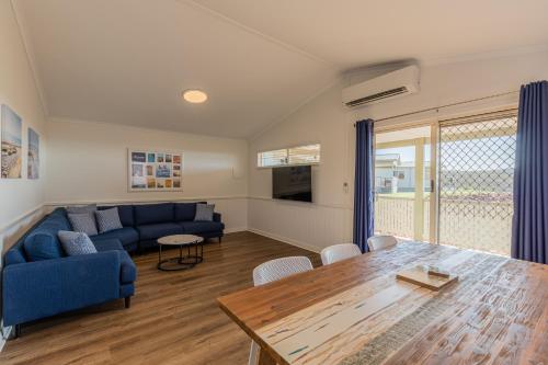 uma sala de estar com um sofá azul e uma mesa em Kalbarri Red Bluff Tourist Park em Kalbarri