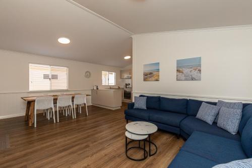 ein Wohnzimmer mit einem blauen Sofa und einem Tisch in der Unterkunft Kalbarri Red Bluff Tourist Park in Kalbarri