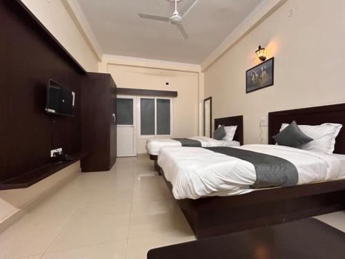 a bedroom with two beds and a television in it at Nath Palace in Varanasi