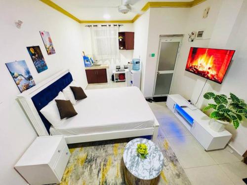 a room with a white bed and a living room at Studio Apartment Bamburi0711519879 Near JSB BlockA in Mombasa