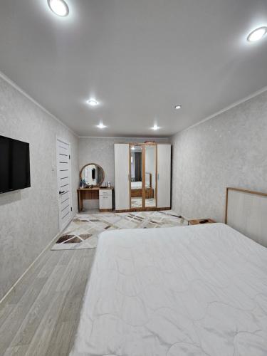 um quarto com uma grande cama branca e uma televisão de ecrã plano em 1 ком квартира ТД Астана em Oral