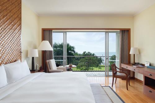 a bedroom with a large bed and a large window at Mandarin Oriental, Sanya in Sanya