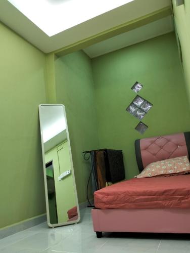 um quarto com um espelho ao lado de uma cama e um espelho em Nik Homestay em Tanah Merah