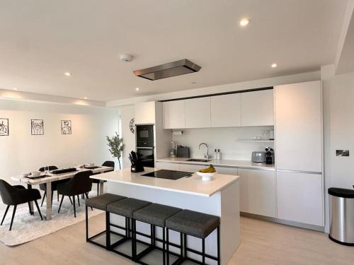 cocina con armarios blancos, mesa y sillas en 34 Cliff Edge 2nd floor Newquay luxury sea-view residence en Newquay
