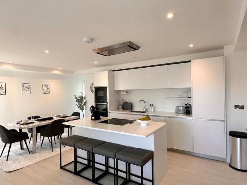 a kitchen with white cabinets and a table and chairs at Quiet Clifftop luxury apartment with partial seaviews in Newquay