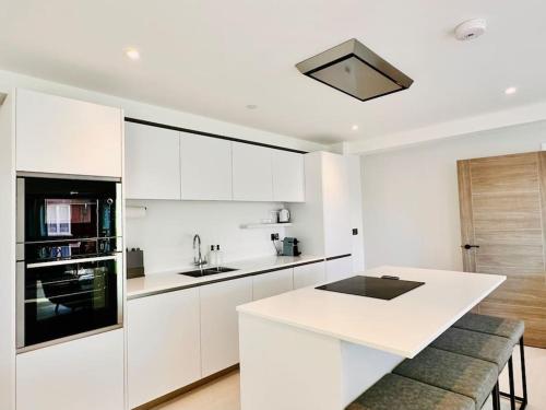 a kitchen with white cabinets and a white counter top at Quiet Clifftop luxury apartment with partial seaviews in Newquay