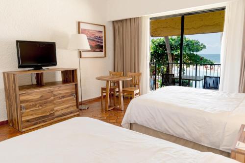a hotel room with two beds and a flat screen tv at Holiday Inn Resort Ixtapa All-Inclusive by IHG in Ixtapa