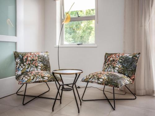 two chairs and a table in a room with a window at Bluemari's Retreat in Hout Bay