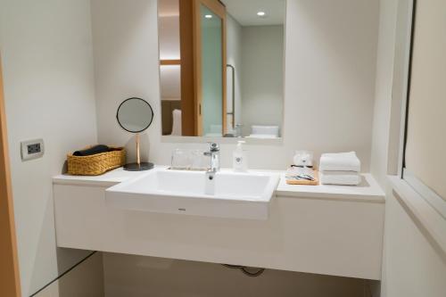 a white bathroom with a sink and a mirror at Nishitetsu Hotel Croom Bangkok Silom in Bangkok
