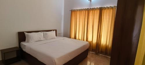 ein Schlafzimmer mit einem Bett und einem gelben Vorhang in der Unterkunft Woodland Escape Villas by Lexstays in Ettumānūr