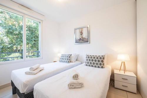 deux lits dans une chambre avec une fenêtre dans l'établissement Beautiful and Spacious 2 bed Apt with Pool, à Antibes