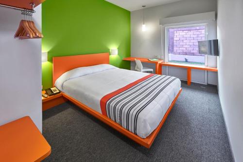 um quarto com uma cama e uma parede verde em City Express Junior by Marriott Toluca Aeropuerto em Toluca