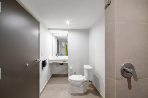 La salle de bains est pourvue de toilettes et d'un lavabo. dans l'établissement City Express Junior by Marriott Toluca Aeropuerto, à Toluca