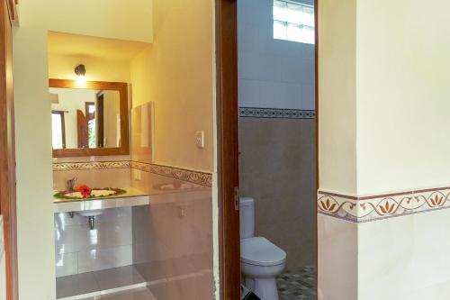 La salle de bains est pourvue de toilettes, d'un lavabo et d'un miroir. dans l'établissement Puri Prana Guest House, à Ubud