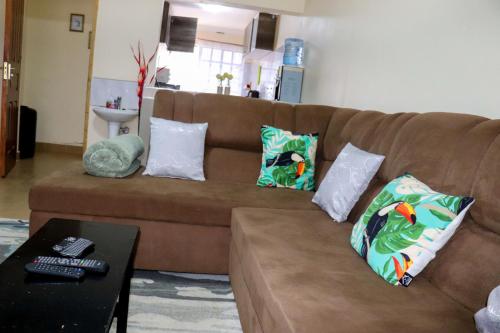 a brown couch with pillows on it in a living room at Fully Furnished 2BR Eclectic Homestay near UOE in Eldoret