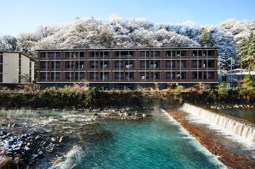 a building next to a river with ducks in the water at Hotel Indigo Hakone Gora by IHG in Hakone
