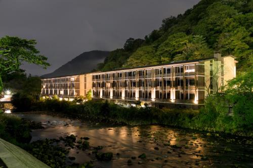 a building next to a river next to a mountain at Hotel Indigo Hakone Gora by IHG in Hakone