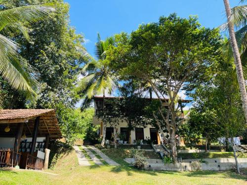 una casa con palmeras delante en Hari Villa Mirissa en Mirissa