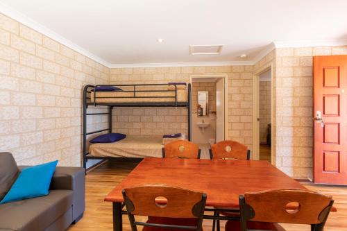 a room with a table and a couch and bunk beds at Kalbarri Tudor Holiday Park in Kalbarri