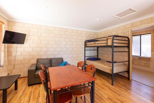 a living room with a table and a couch and bunk beds at Kalbarri Tudor Holiday Park in Kalbarri
