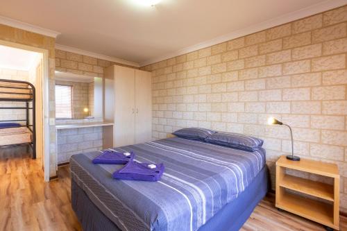 a bedroom with a blue bed with a purple purse on it at Kalbarri Tudor Holiday Park in Kalbarri
