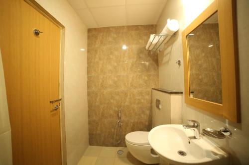 a bathroom with a toilet and a sink and a mirror at IRIS HOTEL BY HOP in Tirupati