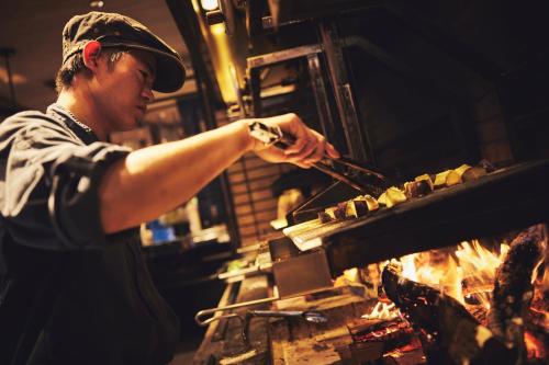 a man is cooking food on a grill at Hotel Indigo Hakone Gora by IHG in Hakone