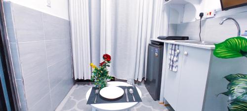 a small bathroom with a toilet and a vase with a flower at Dukes Suites in Nairobi
